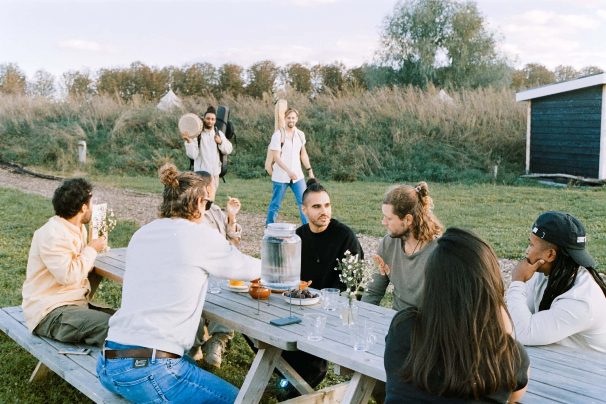 People talking at a long wooden table on the meadow